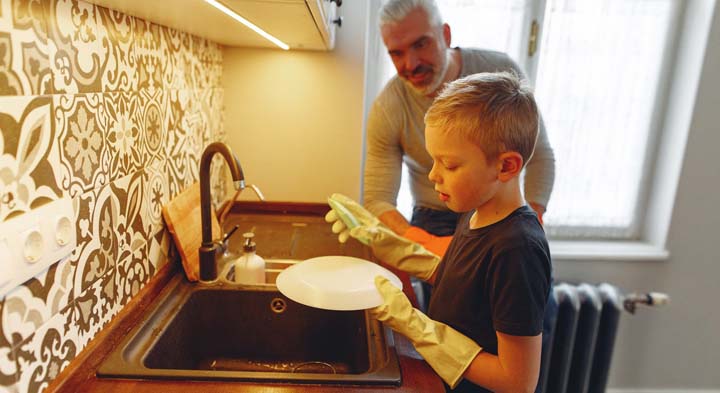 Een kind helpt bij de afwas om een bijdrage te leveren aan de taken van het gezin.