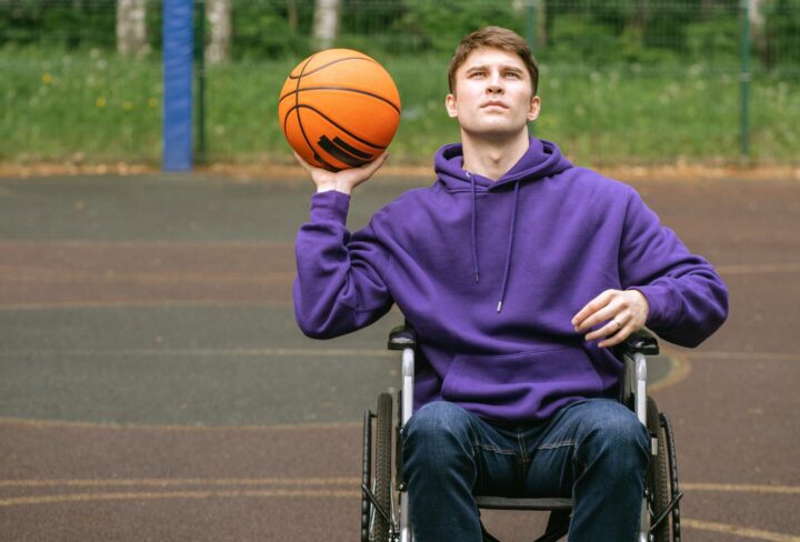 Een man in een rolstoel die basketbal speelt 